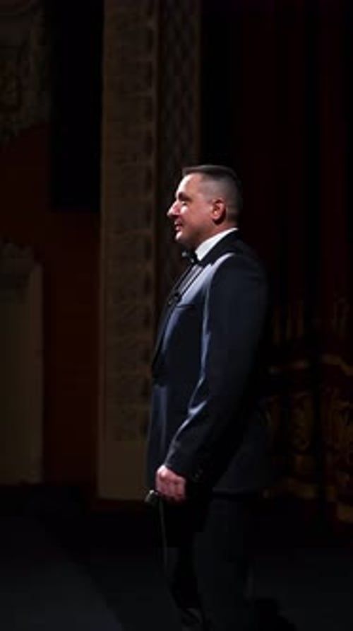 Actor steps on classic theater stage. Man in suit is walking in spotlights during the performance.