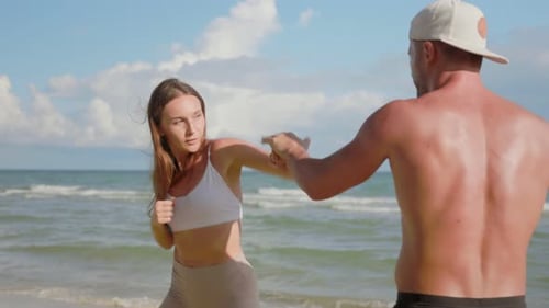 Woman Training Boxing with Man on Beach
