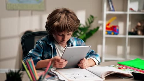 in the Children's Room a Schoolboy in a White Sweater and a Blue Checkered Shirt at a Desk Does