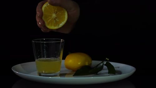 Squeezing Fresh Lemon Juice into Glass