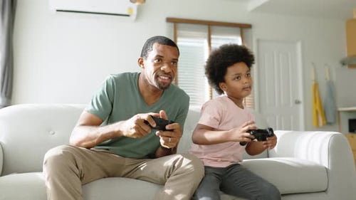 Man and Child Playing Game on Couch Indoors