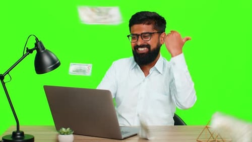 Indian Man Smiling at Laptop Celebrating Jackpot Win While Money Falling Showing Casino Game Victory