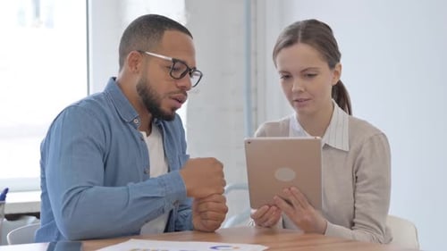 Coworkers Analyzing Data on Tablet in Modern Office