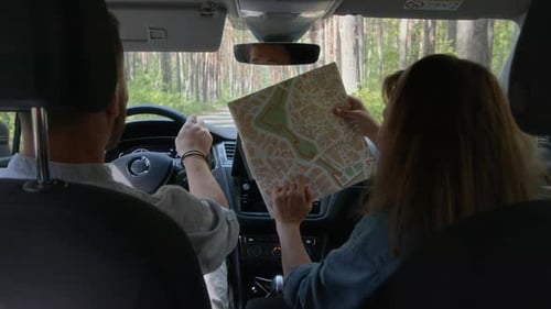 Couple Navigating Scenic Route Through Forest With Map