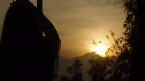 The young woman takes a beautiful sunset over the mountains on her phone. Sea