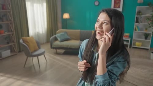 A Young Woman Speaks on a Smartphone Laughs Portrait of an Asian Woman with a Phone to Her Ear Close