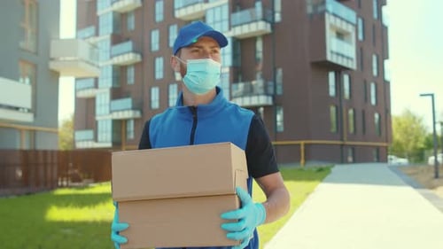 Close Up Delivery Man Holding Cardboard Box at Street Wear Protective Medical Face Mask and Gloves
