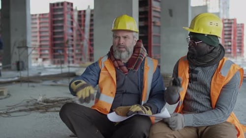 Construction Workers Review Blueprints at Construction Site