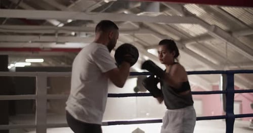 Woman Boxer Punching Pads in a Boxing Ring