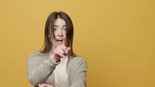 Young Woman Pointing at Camera on Yellow Background