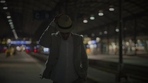 Stylish Man Wearing Hat at Train Station at Night