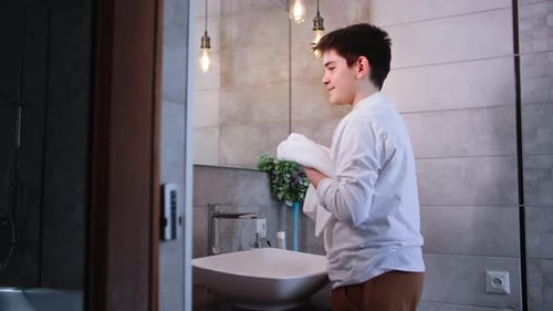 Young Person Drying Face with Towel in Bathroom