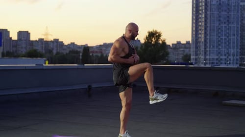 Muscular Man Exercising on Rooftop at Sunrise