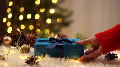 Woman places Christmas gift on soft white surface
