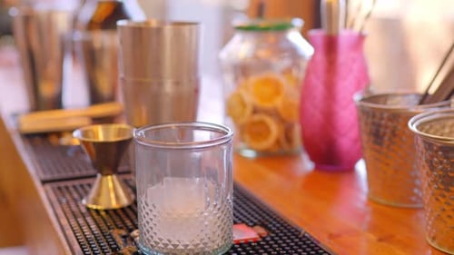 barwoman pouring large ice cubes into a glass for a drink