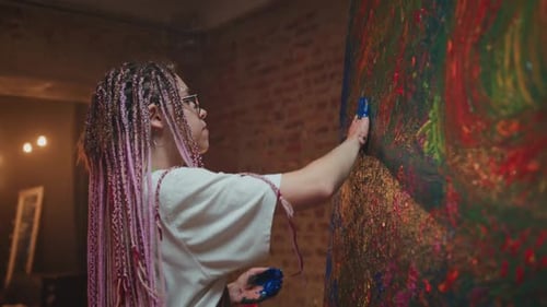 Female Artist Adds Blue Paint on Huge Picture in Workshop