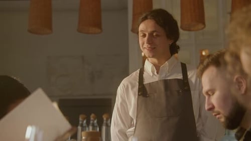 Waiter Smiles and Serves Group of Friends in Cafe