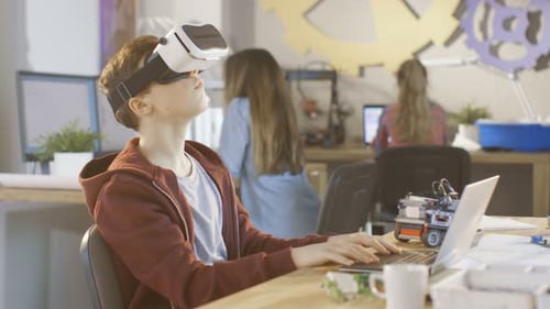 In a Computer Science Class Boy Wearing Virtual Reality Headset Works on a Programing Project.