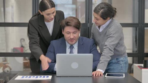 Business Colleagues Reviewing Laptop at Office Desk