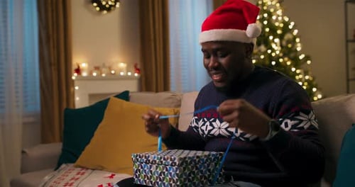 Man Unwraps Christmas Gift in Cozy Home