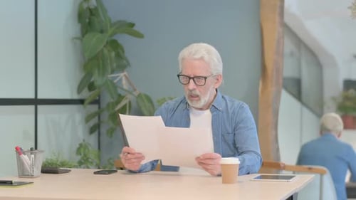 Older Man Reviews Documents in Office