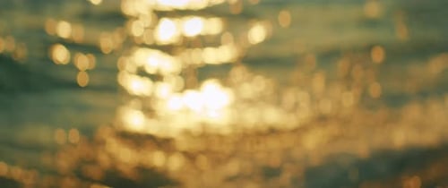 Sunlight reflecting on ocean surface creating bright bokeh effect in the morning