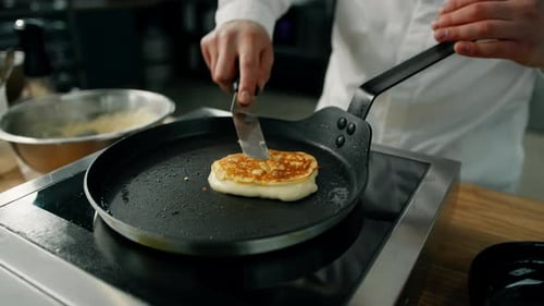 Chef cooking golden pancake on a frying pan