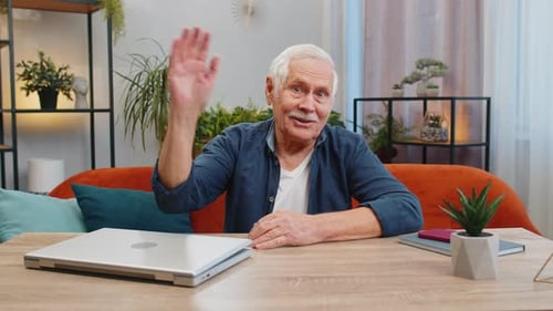 Friendly Senior Man Waving and Smiling at Home