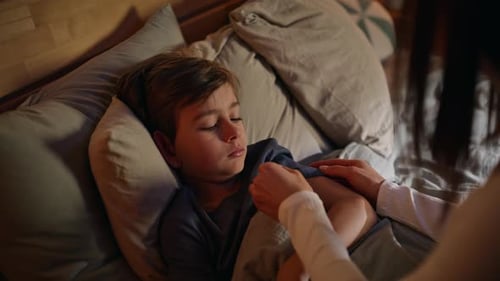 Sick Child Lying in Bed; Mother Checks Temperature