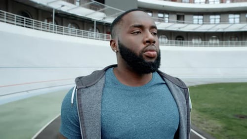 Portrait Of Serious Male Athlete Standing On Racetrack. Sporty Afro Man Jogging At Stadium Track....