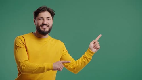Bearded Smiling Man Presenting Something Isolated on Green Background Portrait of Guy He Pointing