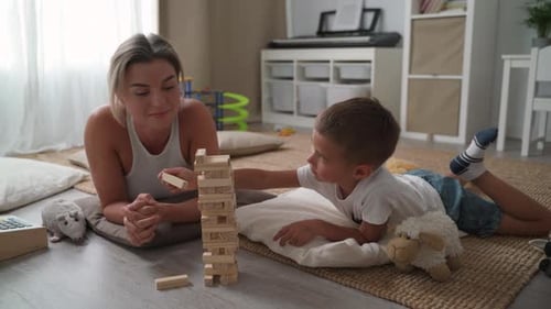Woman and Boy Playing Stacking Game on Floor
