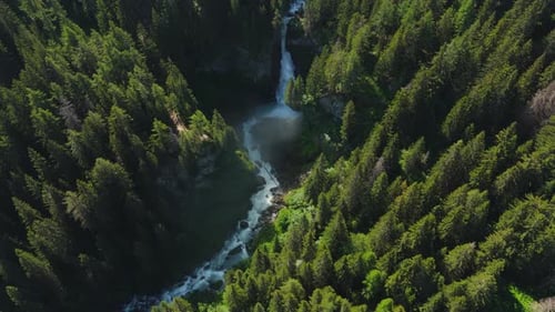 A waterfall cascading through a dense green forest, aerial view