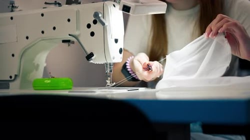 Close Up in the Sewing Workshop Young Girl Works with a Sewing Machine and White Fabric