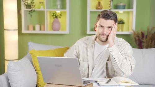 Man Works At Laptop On Couch At Home