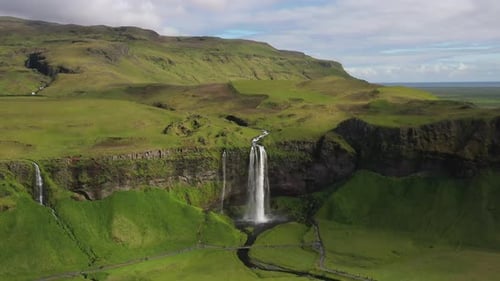 Majestic Waterfall Cascades Down Lush Green Icelandic Mountainside Scenery