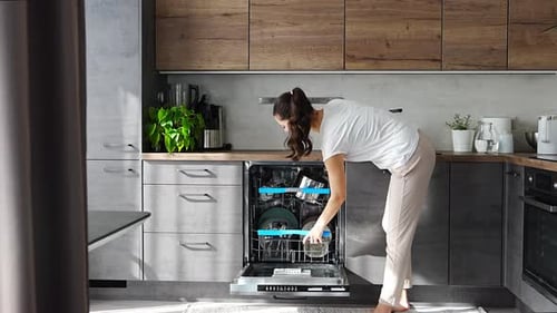 Woman Unloading Dishwasher in Modern Kitchen