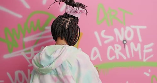 Young Woman Creating Graffiti Art on Pink Wall