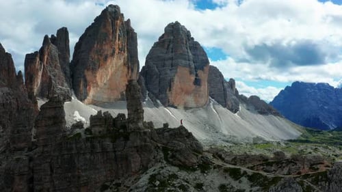 Triumphant man stands on cliff, Italy Dolomites in distance