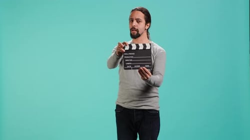 Man Holding Film Slate Against Blue Background