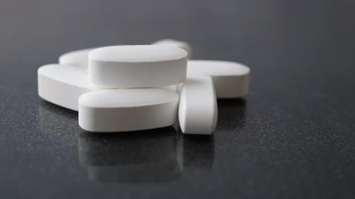 Stack of White Oval Pills on Dark Surface