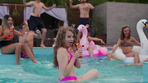 Pretty Woman in Bikini Drinking Cocktail and Hanging Out with Friends at Night Pool Party People