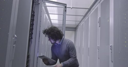 Technician with Tablet Inspecting Servers in Data Center