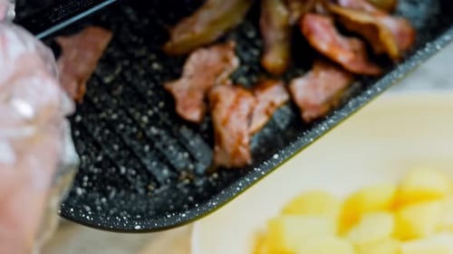 La mujer pone tocino marinado frito sobre la ensalada