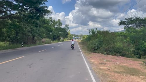 Back view of women cycling in the jungle street of Laos.