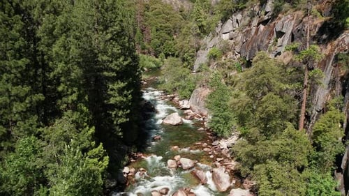 Low aerial shot flying up a fast flowing whitewater mountain river. 4K