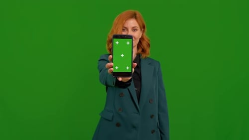 Woman displays the phone with chroma key screen showing it to camera.