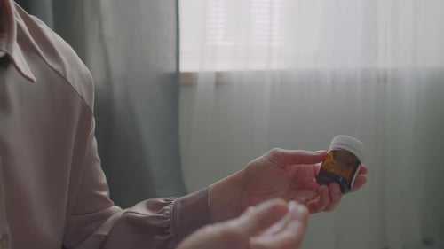 Woman Examining Pills Bottle in Home Setting