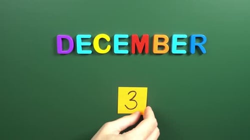 Hand sticking a sticker 3 December calendar day on school board. 3 date of December. Third day