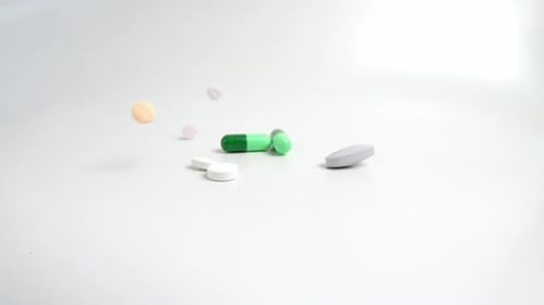 Verschiedene bunte Pillen und Medikamente, die auf weißen Hintergrund fallen